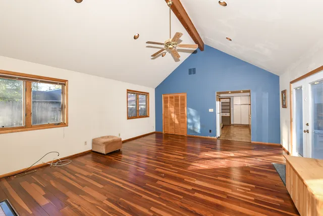 a view of empty room with wooden floor and fan