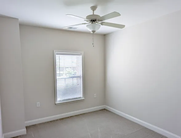 an empty room with a window and a fan