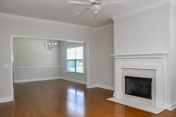 an empty room with wooden floor fireplace and windows