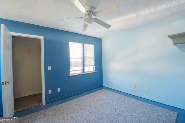 an empty room with a ceiling fan and a window