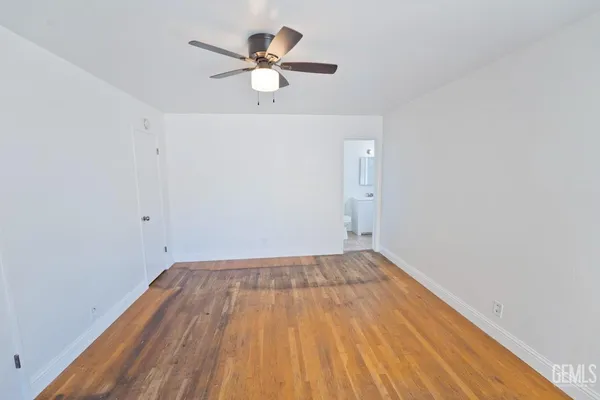 an empty room with wooden floor and a ceiling fan