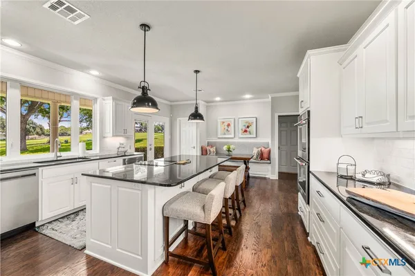 a kitchen with stainless steel appliances kitchen island granite countertop a stove and a sink