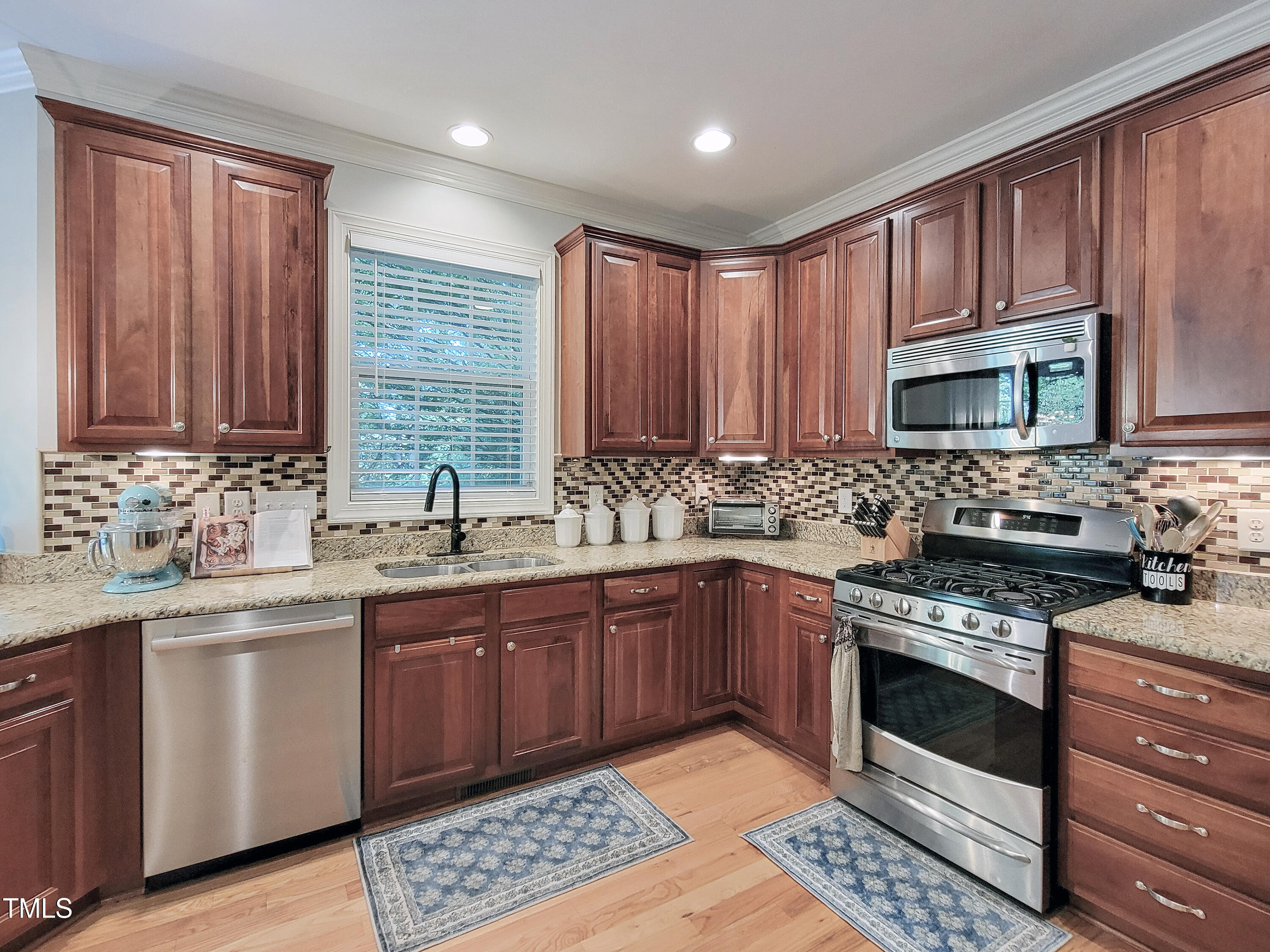 7502 Hedfield Way Durham, NC 27713 - Photo 5 of 28 a kitchen with stainless steel appliances kitchen island granite countertop a sink stove and microwave