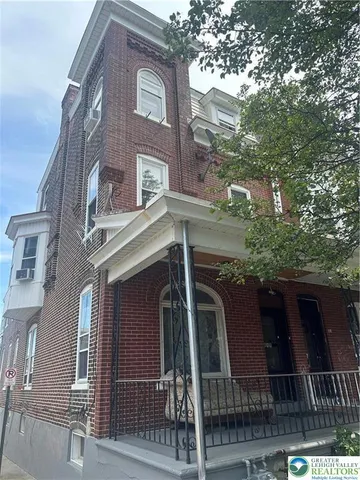 a front view of a house with a tree