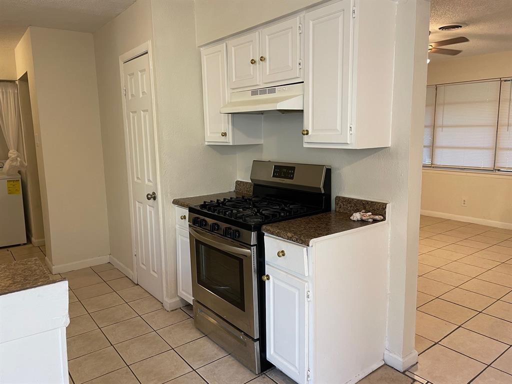 102 Roma Drive Garland, TX 75041 - Photo 4 of 9 Kitchen featuring white cabinetry, stone-finish countertops, and a stainless steel gas range with an overhead vent