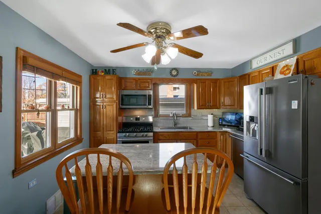 a kitchen with stainless steel appliances granite countertop a refrigerator a stove a sink a dining table and chairs with wooden floor