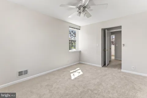 an empty room with a chandelier fan and windows