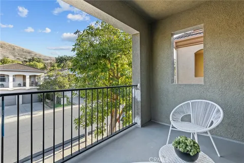 a balcony with chairs and a potted plant