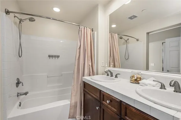 a bathroom with a granite countertop sink mirror and a bathtub