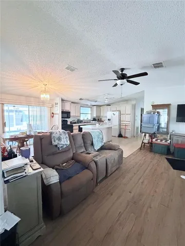 a living room with stainless steel appliances kitchen island granite countertop a table chairs and a refrigerator