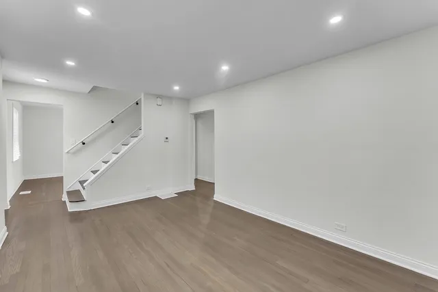 an empty room with wooden floor and staircase