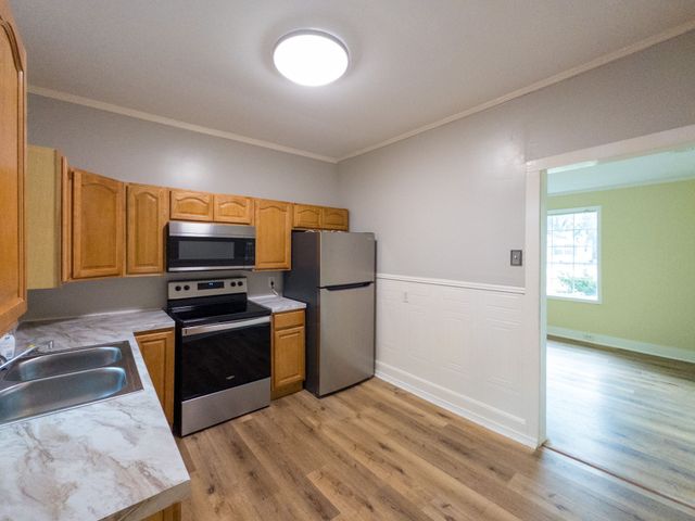 a kitchen with wooden floors and stainless steel appliances