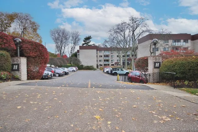 a view of road with card parked on side and retail shops