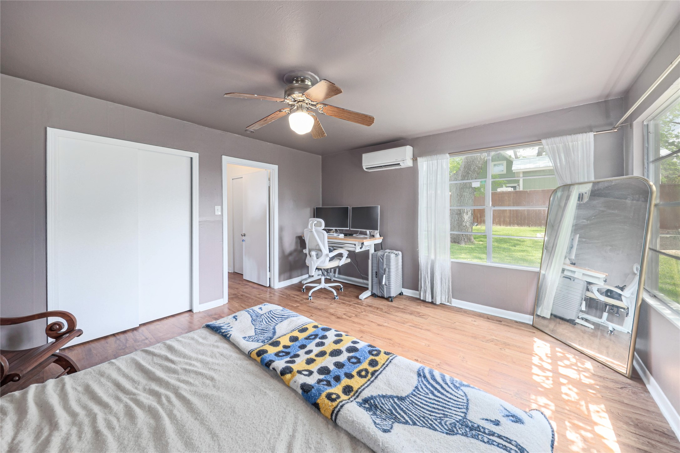 4607 Evans Avenue, Unit B Austin, TX 78751 - Photo 13 of 34 Spacious room featuring wood-finish flooring, a ceiling fan with integrated lighting, and multiple windows providing natural light