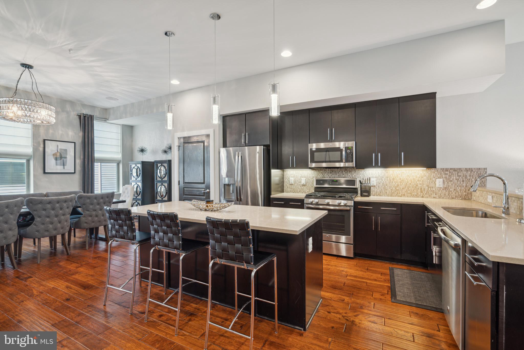 a kitchen with granite countertop a dining table chairs wooden floor and stainless steel appliances
