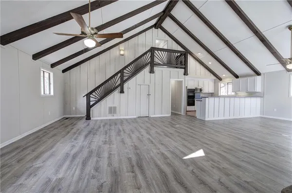 an empty room with wooden floor fireplace and windows