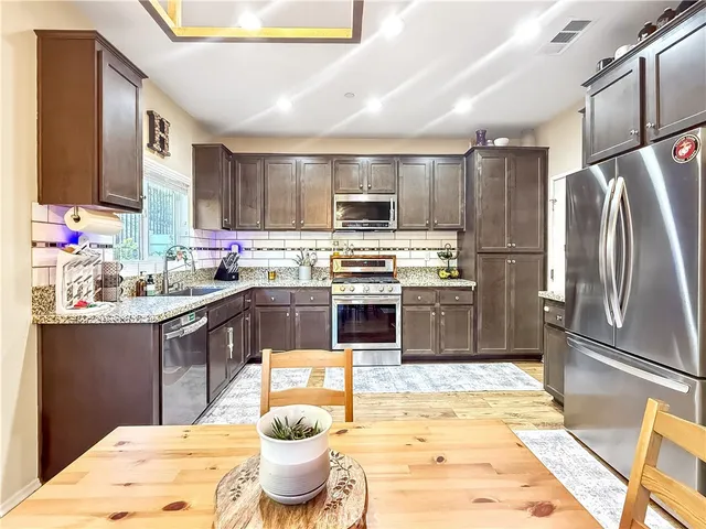 a kitchen with stainless steel appliances kitchen island granite countertop a sink stove and refrigerator