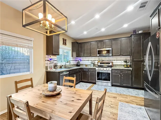 a kitchen with stainless steel appliances kitchen island granite countertop a sink dishwasher a stove a refrigerator with a dining table and chairs