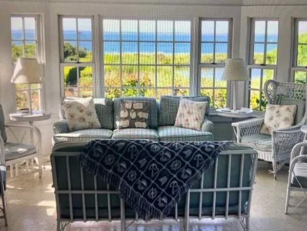 a living room with furniture large windows and wooden floor