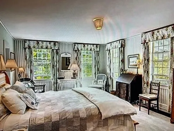 a bedroom with a bed a large window with table and chair