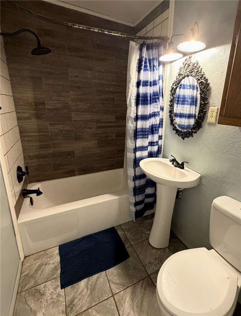 5108 Ridge Road Alma, AR 72921 - Photo 16 of 33 Bathroom featuring a white bathtub with dark bronze fixtures, wood-finish tile shower surround, and a ceramic pedestal sink with dark bronze faucet