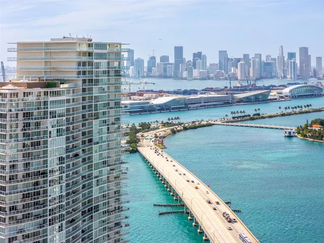 a view of patio with swimming pool table and chairs under palm trees