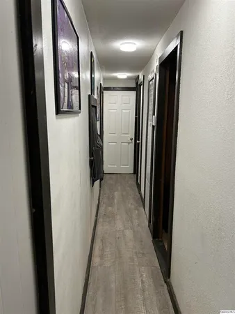 a view of hallway with stainless steel appliances wooden floor and staircase