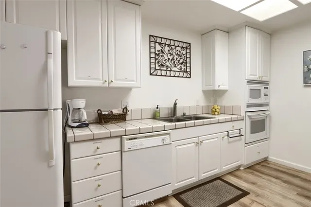 a kitchen with granite countertop white cabinets and white appliances