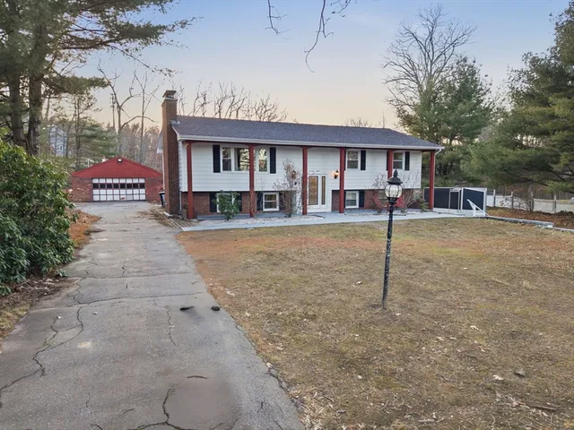 a front view of a building with a yard and trees