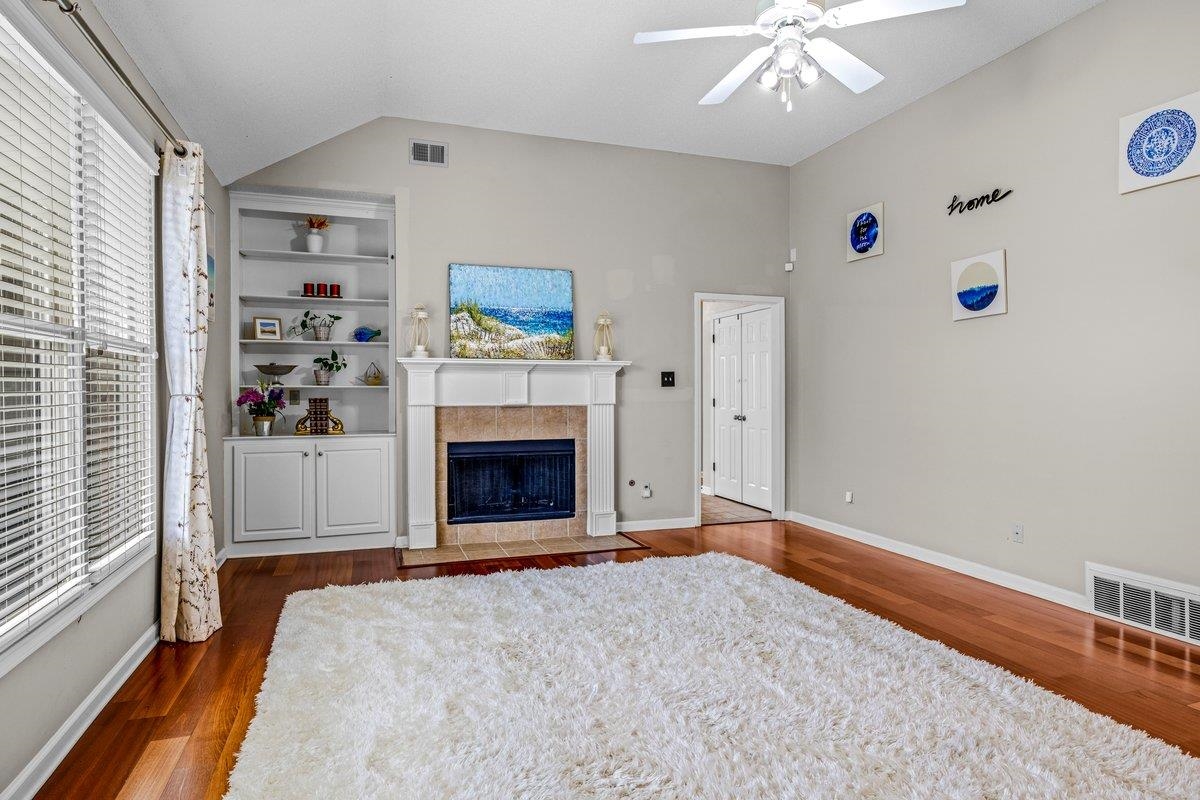 4840 Rainy Pass Road Collierville, TN 38017 - Photo 6 of 30 Spacious living area featuring a fireplace with a white mantel and tiled surround, built-in shelving, wood-finish flooring, and a ceiling fan