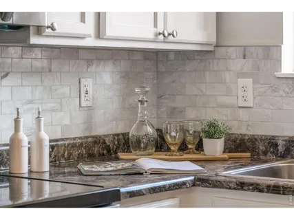 a kitchen with granite countertop white cabinets sink and stainless steel appliances