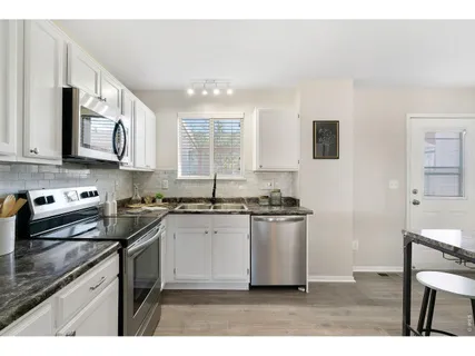 a kitchen with granite countertop a refrigerator stove top oven and sink
