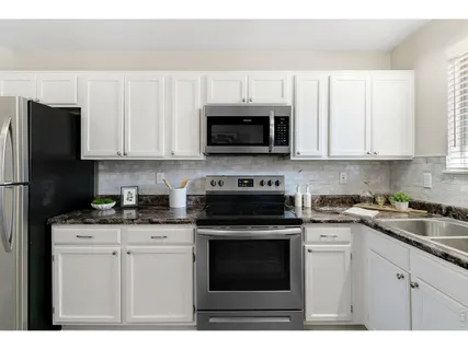 a kitchen with kitchen island a stove a sink a microwave a dining table and chairs