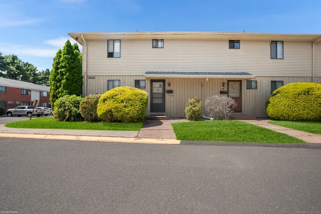 front view of a house with a yard and potted plants