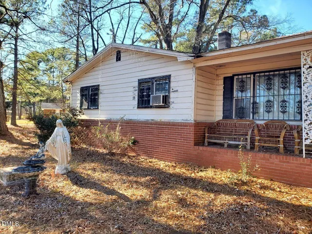 a backyard of a house with wooden fence and large trees