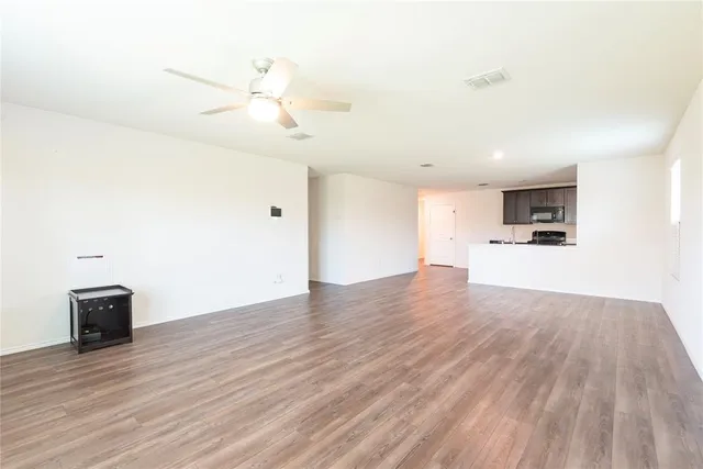 a view of kitchen and empty room with wooden floor