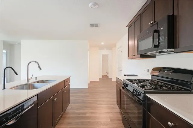 a kitchen with stainless steel appliances a sink a stove a microwave a sink and a refrigerator