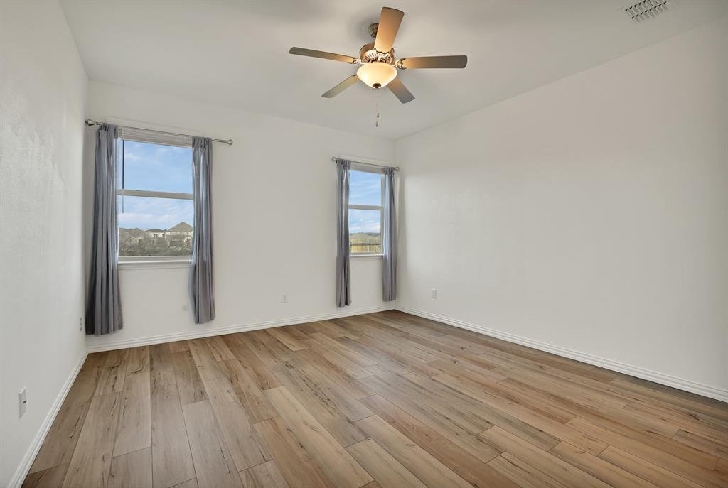 3204 Renaissance Drive Denton, TX 76207 - Photo 12 of 25 Spacious room featuring wood-finish flooring, white walls, and a ceiling fan with integrated lighting