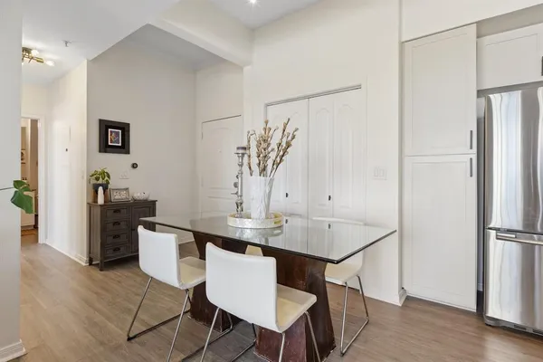 a room with stainless steel appliances kitchen island a table chairs and a refrigerator