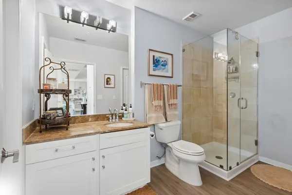 a bathroom with a toilet sink vanity granite and shower