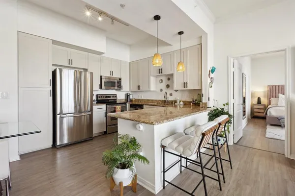 a kitchen with stainless steel appliances granite countertop a refrigerator a stove a sink a dining table and chairs with wooden floor