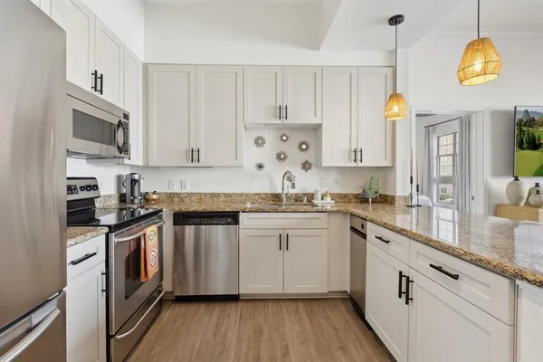 a kitchen with stainless steel appliances granite countertop a stove a sink and a granite counter tops with wooden floors