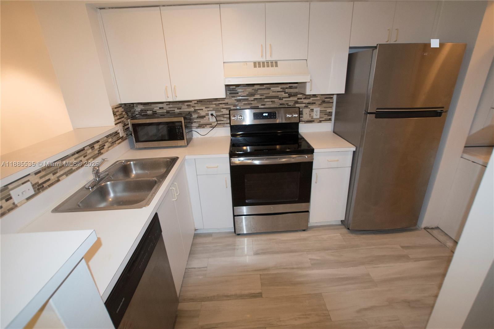 12130 St Andrews Place, Unit 101 Miramar, FL 33025 - Photo 2 of 13 a kitchen with a sink stove and refrigerator