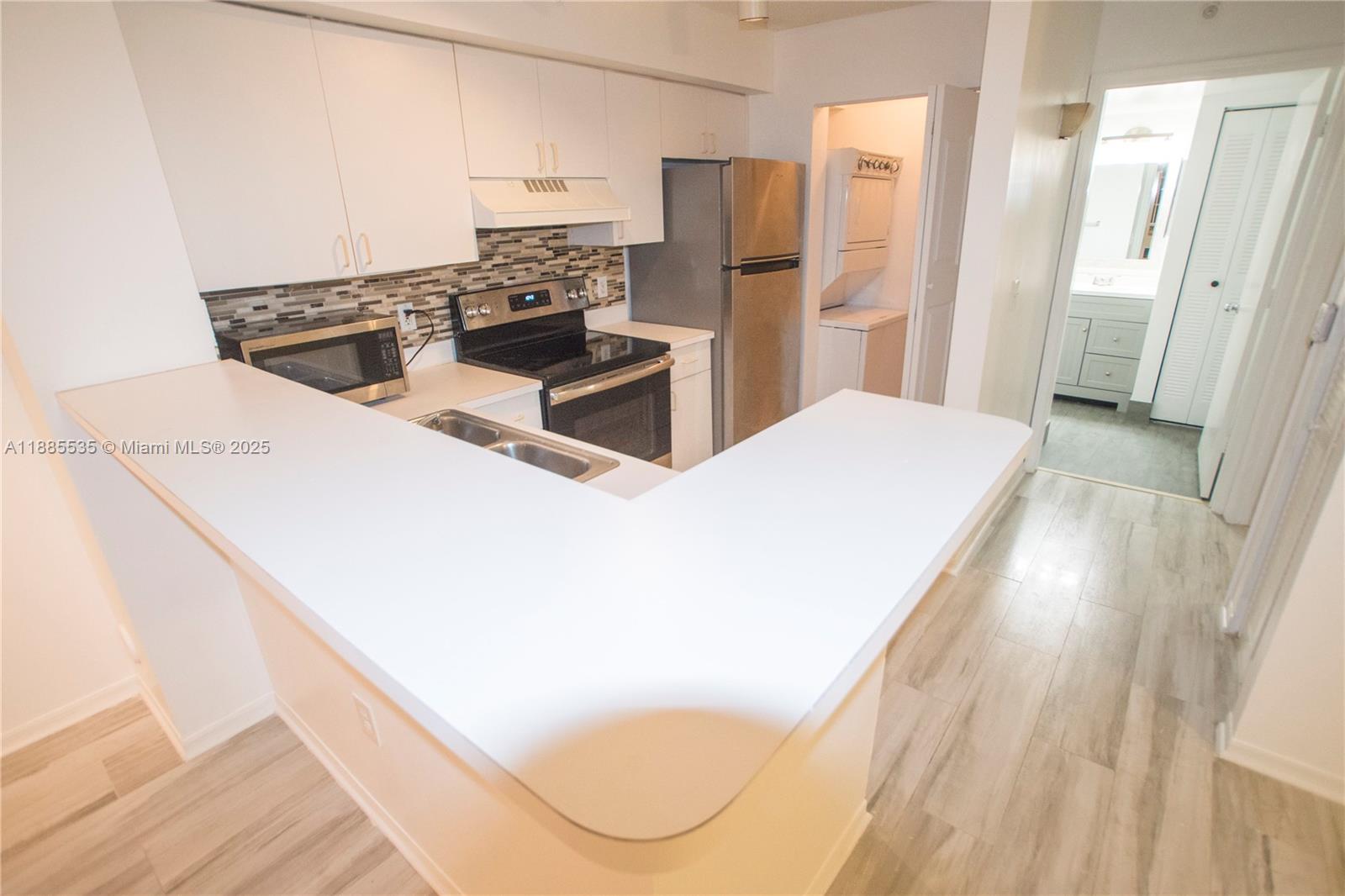 12130 St Andrews Place, Unit 101 Miramar, FL 33025 - Photo 3 of 13 a kitchen with stainless steel appliances a refrigerator a stove a sink and white cabinets