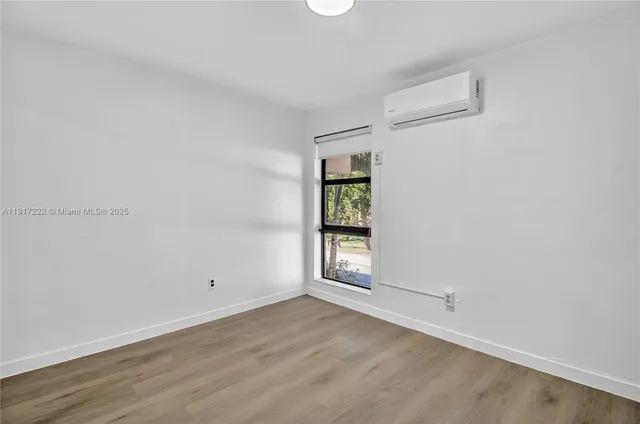 an empty room with wooden floor and window