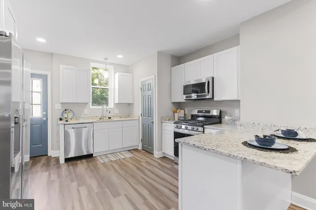 a kitchen with a sink wooden floor and stainless steel appliances
