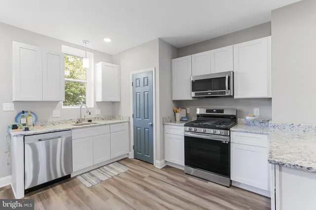 a kitchen with stainless steel appliances granite countertop a stove a sink and a microwave