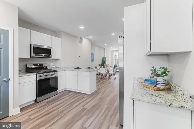 a kitchen with a microwave a stove top oven a sink dishwasher and a refrigerator with wooden floor