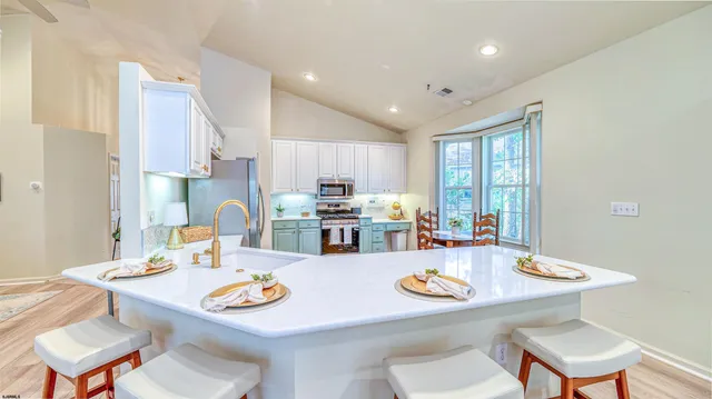 a kitchen with stainless steel appliances granite countertop a stove top oven a sink a dining table and chairs with wooden floor