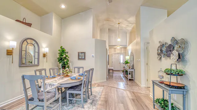 a kitchen with stainless steel appliances granite countertop a refrigerator a sink dishwasher a stove and a dining table with wooden floor